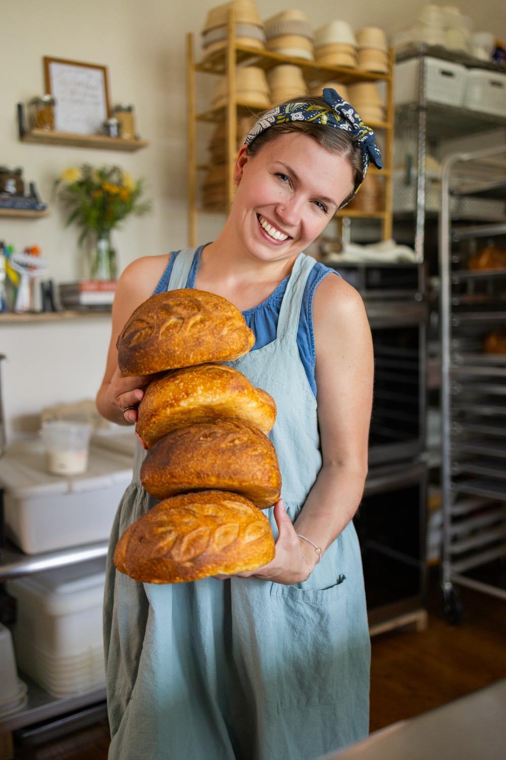 Caroline holding a stack of fresh sourdough loaves